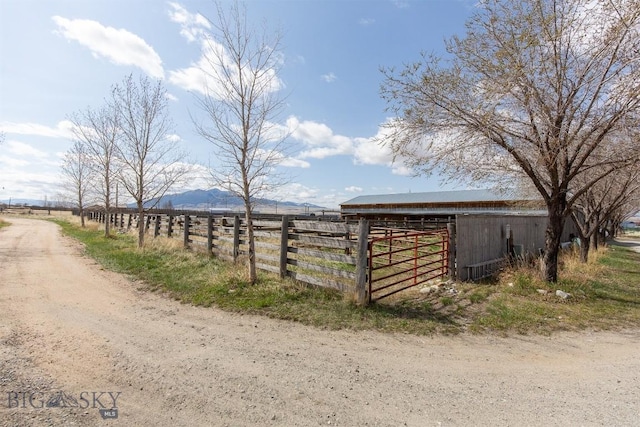 view of outbuilding featuring an outdoor structure, a mountain view, and fence