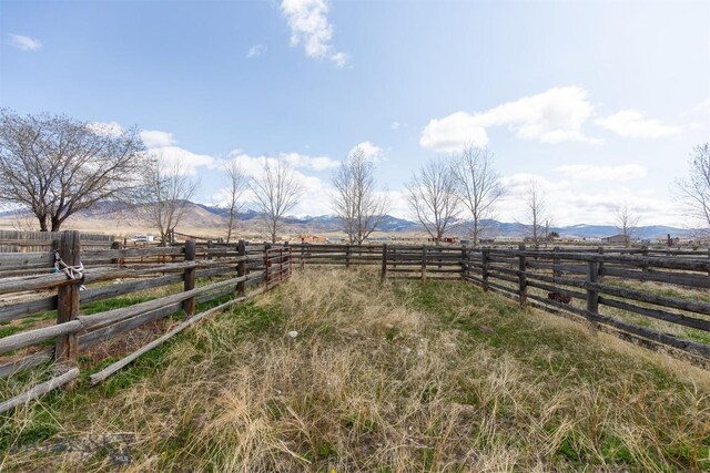view of yard with fence, a rural view, and a mountain view