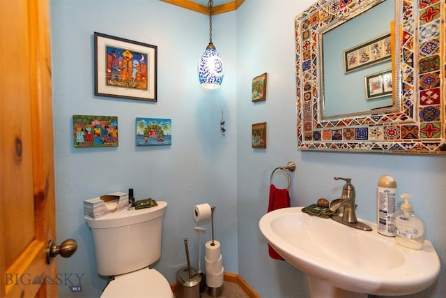 half bath with toilet, baseboards, and a sink