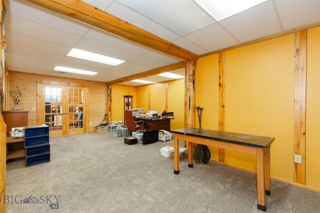 office area featuring wooden walls, carpet flooring, a drop ceiling, and french doors