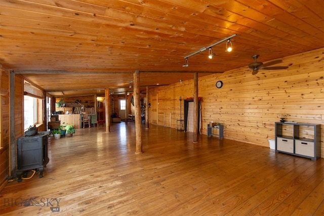 misc room featuring wood ceiling, hardwood / wood-style floors, wood walls, ceiling fan, and a wood stove