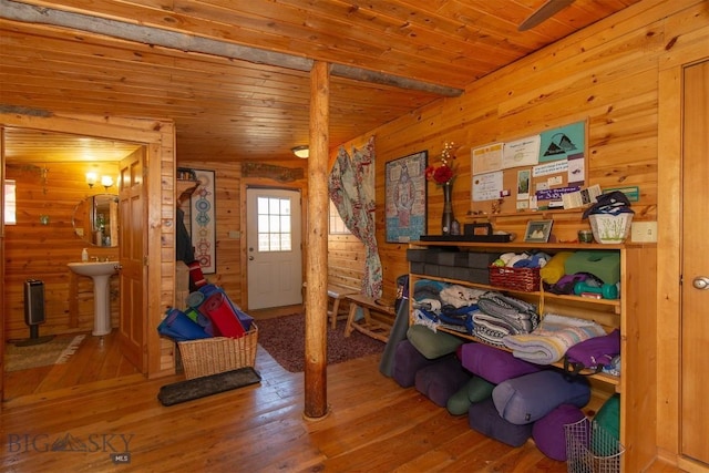 interior space featuring a sink, wooden walls, hardwood / wood-style floors, and wooden ceiling