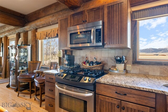 6 Browtine Ln, Ennis, MT 59729 - kitchen with beam ceiling, decorative backsplash, light wood-type flooring, a mountain view, and appliances with stainless steel finishes