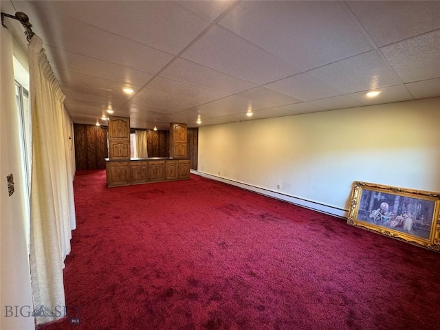 unfurnished living room featuring recessed lighting, a drop ceiling, dark colored carpet, and a baseboard radiator
