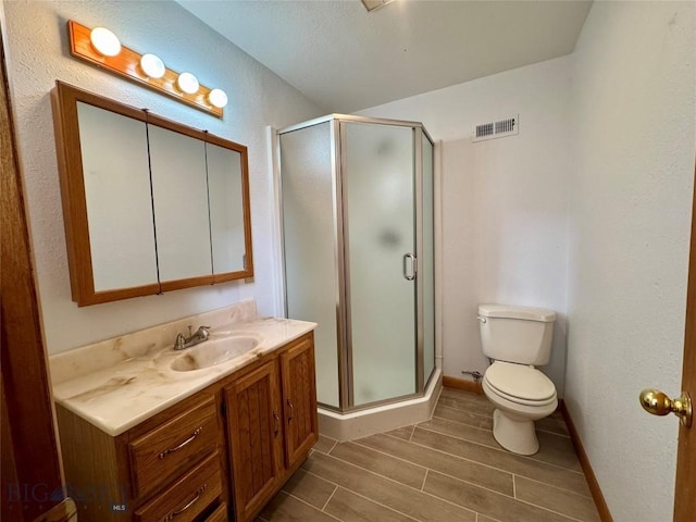 bathroom with visible vents, toilet, a shower stall, and vanity