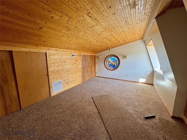additional living space with wood walls, visible vents, carpet flooring, and wood ceiling