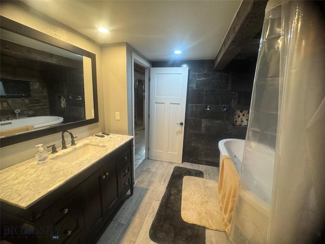 full bath featuring recessed lighting, a tub, wood finished floors, and vanity