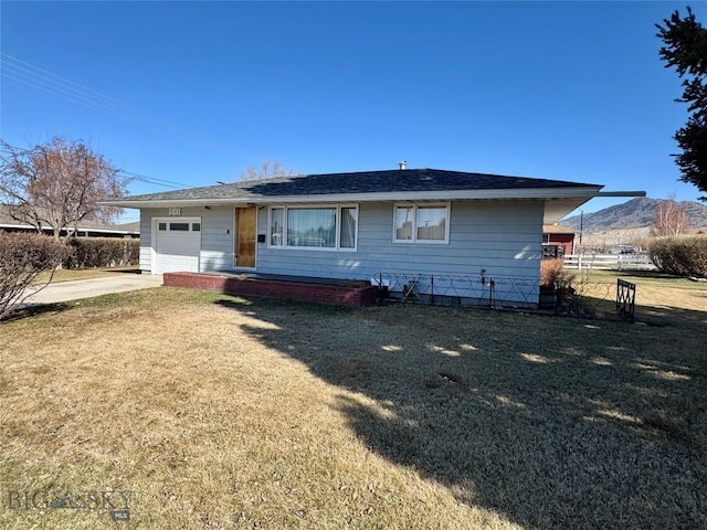 rear view of property with a lawn, driveway, roof with shingles, an attached garage, and fence
