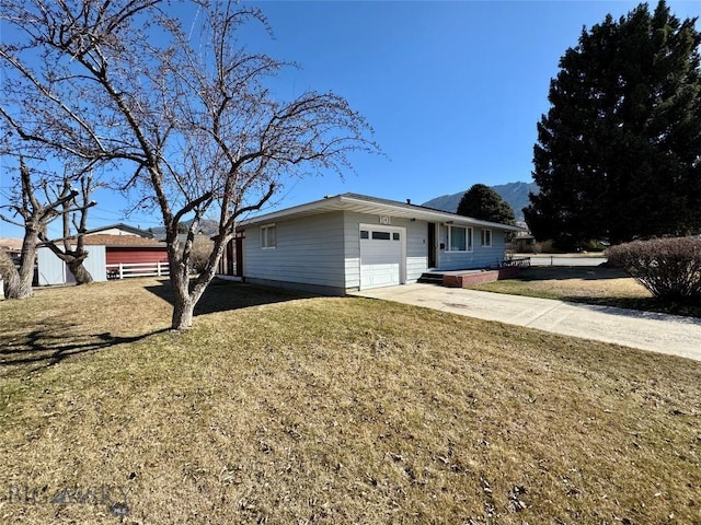 view of front of house with a front lawn, an attached garage, concrete driveway, and a mountain view