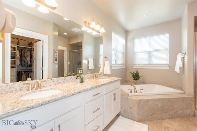 full bath featuring a garden tub, a sink, a shower stall, and a spacious closet
