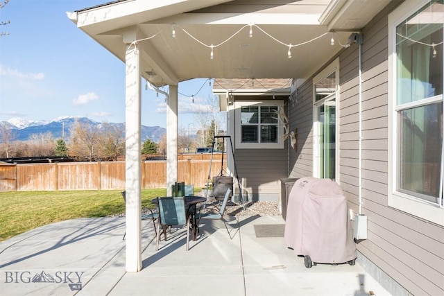 view of patio with fence, a mountain view, and outdoor dining area