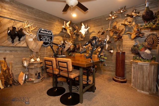 wine cellar featuring wooden walls, a ceiling fan, and carpet