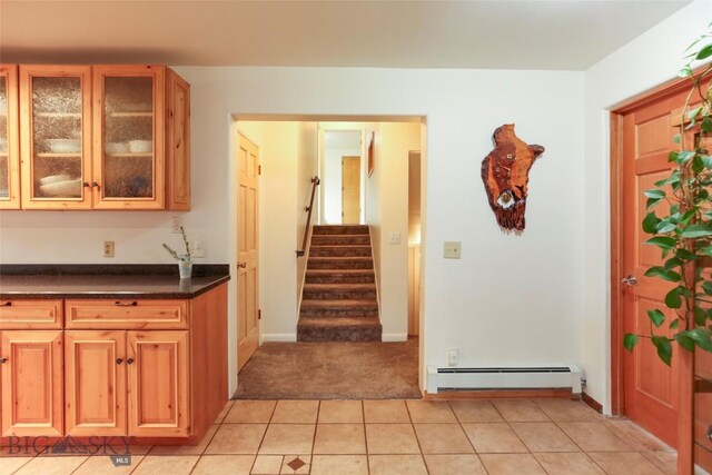 726 US Highway 10 W, Livingston, MT 59047 - kitchen with a baseboard radiator, dark countertops, light colored carpet, glass insert cabinets, and light tile patterned floors