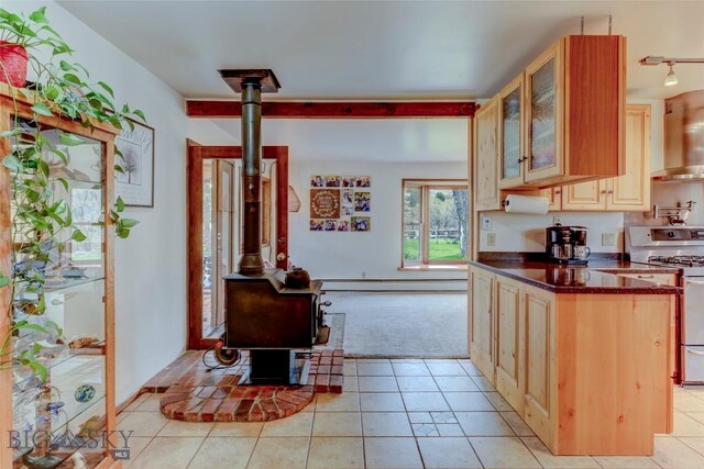 726 US Highway 10 W, Livingston, MT 59047 - kitchen with a wood stove, range with gas stovetop, wall chimney range hood, dark countertops, and light colored carpet