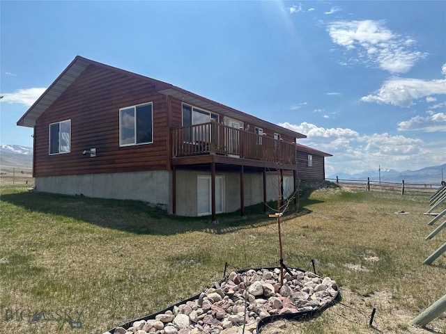 view of home's exterior featuring a lawn, a deck with mountain view, and fence
