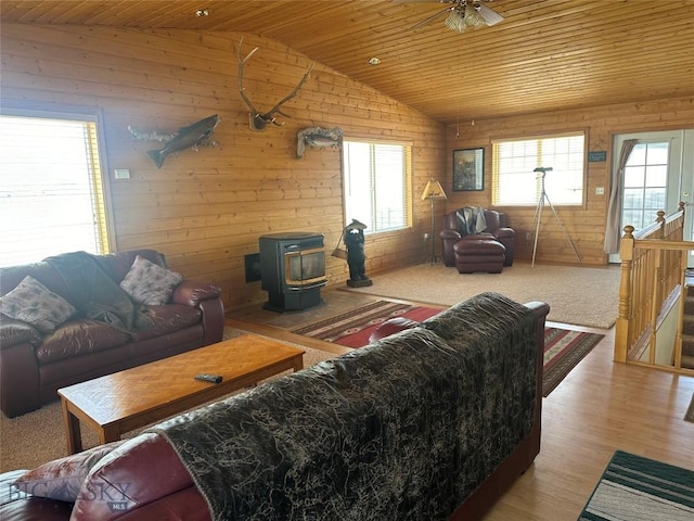 living room featuring wood ceiling, plenty of natural light, and a wood stove