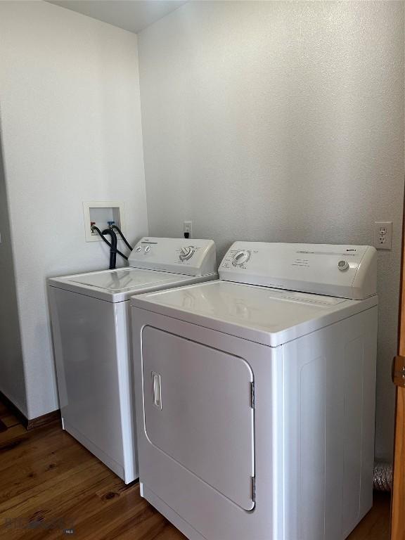 washroom featuring baseboards, wood finished floors, washing machine and clothes dryer, and laundry area