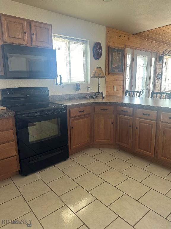 kitchen with light tile patterned floors, black appliances, and brown cabinetry