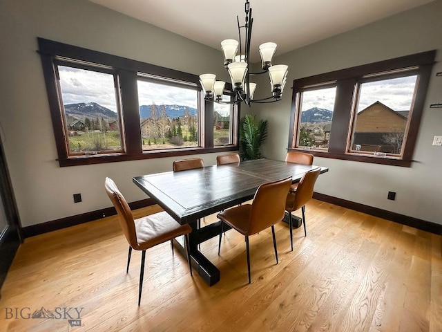 dining room featuring light wood finished floors, a notable chandelier, and baseboards