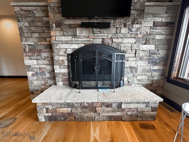 details featuring a fireplace, wood finished floors, and baseboards