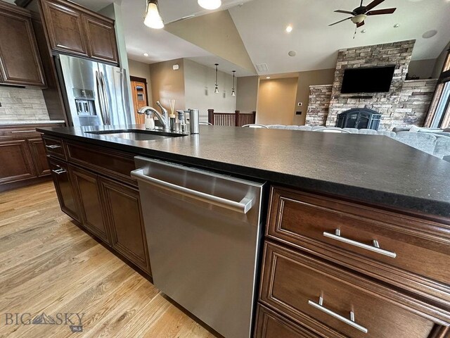 kitchen with a sink, ceiling fan, light wood-style flooring, appliances with stainless steel finishes, and open floor plan