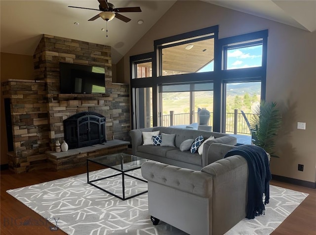 living area with a fireplace, wood finished floors, ceiling fan, and vaulted ceiling