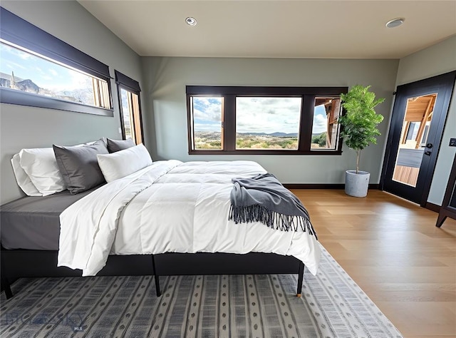 bedroom with baseboards, recessed lighting, wood finished floors, and multiple windows