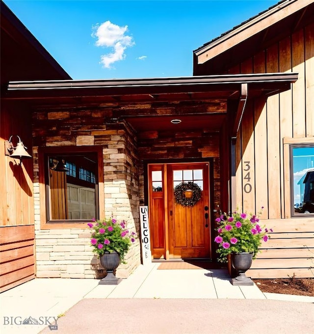 view of exterior entry with board and batten siding and stone siding