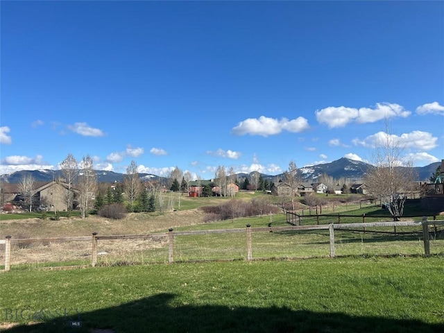 view of yard with fence, a rural view, and a mountain view