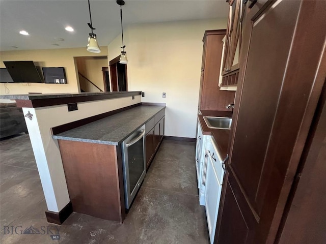 kitchen with a sink, dark countertops, concrete flooring, and baseboards