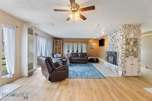 living room with a textured ceiling, a heating unit, ceiling fan, and wood finished floors