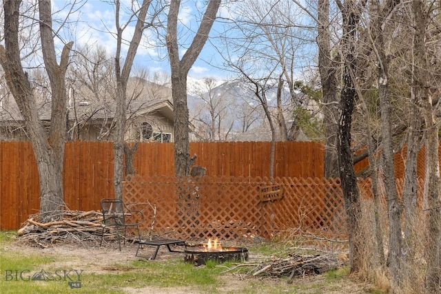 view of yard with fence, a mountain view, and an outdoor fire pit