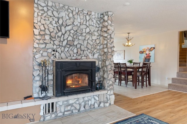 interior details featuring a fireplace, a notable chandelier, a textured ceiling, and wood finished floors