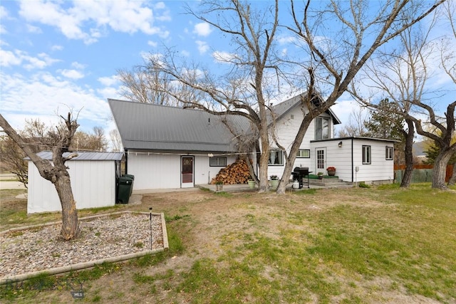 rear view of house featuring a lawn and metal roof