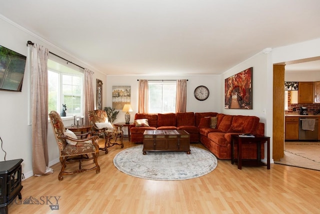 living area with crown molding and light wood-style flooring