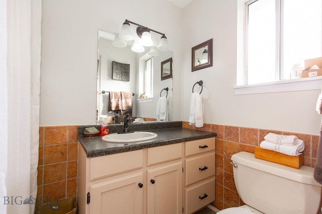 bathroom featuring tile walls, wainscoting, and a wealth of natural light
