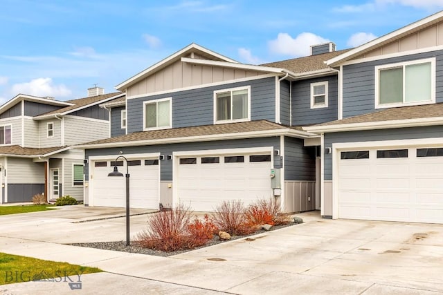1307 Grover Ln Unit B, Belgrade, MT 59714 - view of front of house featuring a garage, board and batten siding, a chimney, and concrete driveway