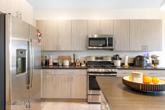 1307 Grover Ln Unit B, Belgrade, MT 59714 - kitchen featuring stainless steel appliances, dark countertops, light wood-style flooring, and light brown cabinets