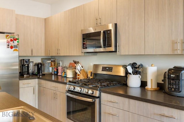 1307 Grover Ln Unit B, Belgrade, MT 59714 - kitchen featuring light brown cabinetry, dark countertops, and appliances with stainless steel finishes