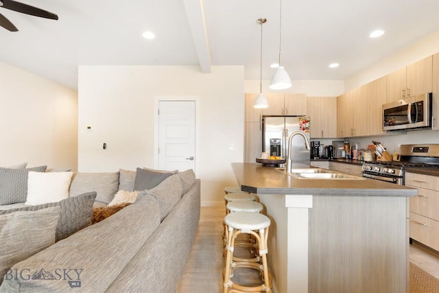 1307 Grover Ln Unit B, Belgrade, MT 59714 - kitchen featuring light brown cabinetry, open floor plan, a kitchen breakfast bar, a sink, and appliances with stainless steel finishes