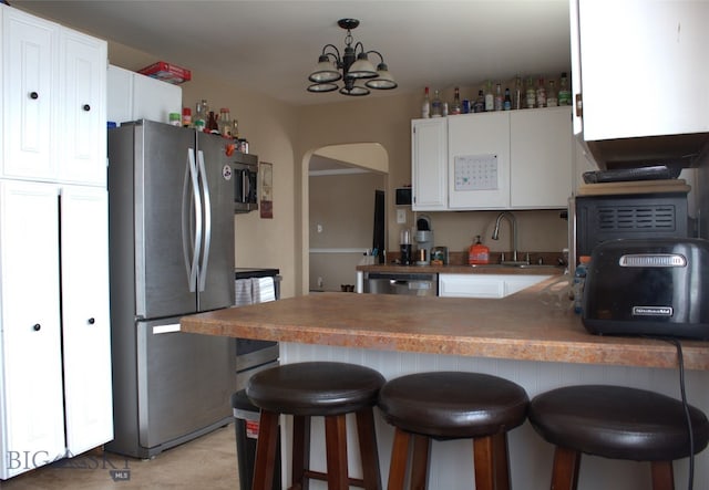 820 Lexington Ave, Butte, MT 59701 - kitchen with arched walkways, a sink, white cabinets, a peninsula, and stainless steel appliances