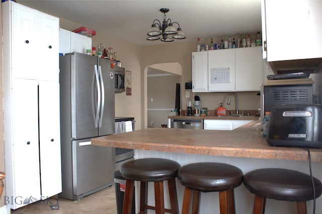820 Lexington Ave, Butte, MT 59701 - kitchen featuring a sink, a peninsula, white cabinetry, arched walkways, and appliances with stainless steel finishes