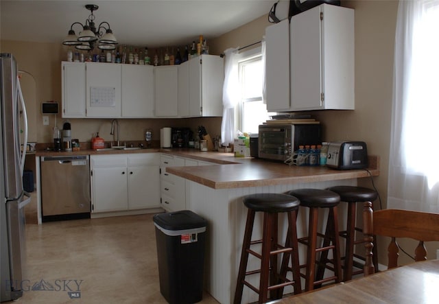 820 Lexington Ave, Butte, MT 59701 - kitchen with white cabinets, an inviting chandelier, a sink, stainless steel appliances, and a peninsula