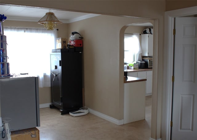820 Lexington Ave, Butte, MT 59701 - kitchen featuring crown molding, an inviting chandelier, baseboards, white cabinets, and arched walkways