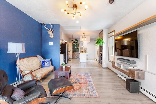 living area with light wood-type flooring, a baseboard radiator, baseboards, and a chandelier