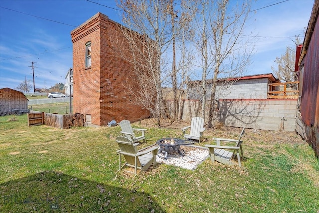 view of yard with fence, an outbuilding, a fire pit, and a storage shed