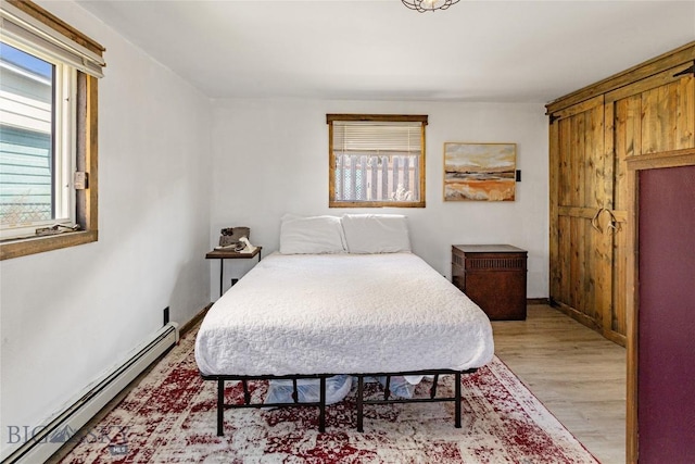 bedroom featuring baseboard heating and light wood finished floors
