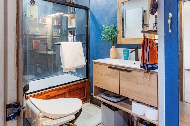 bathroom featuring vanity, a textured wall, and enclosed tub / shower combo