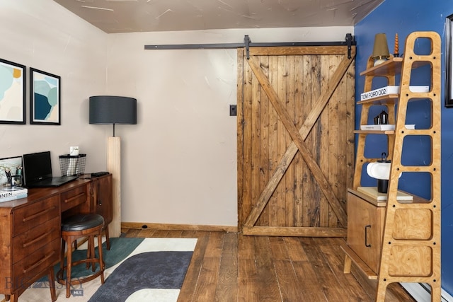 office space featuring a barn door, baseboards, and hardwood / wood-style floors