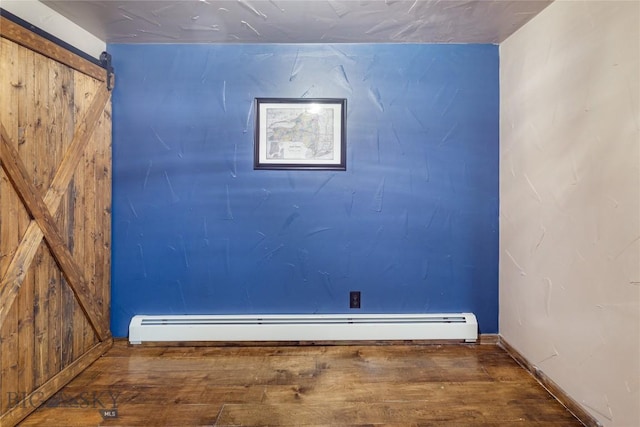 interior space featuring wood finished floors, a barn door, and a baseboard heating unit